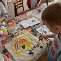 Chłopiec maluje torbe farbami.