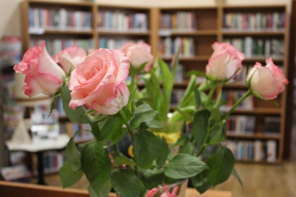 róże w bibliotece na tle regałów z książkami