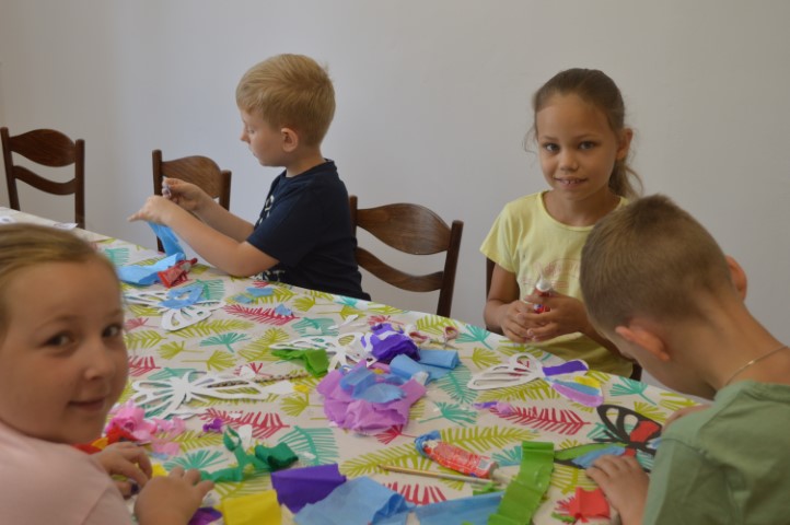 Dzieci przy stole wycinają kolorowe motyle z papieru