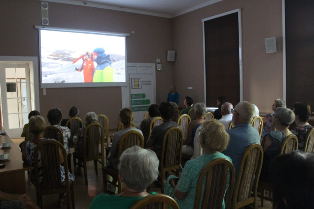 Publiczność ogląda prezentacje na dużym ekranie w budynku 