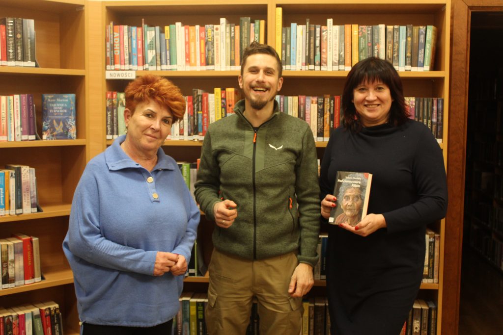 troje ludzi (dwie kobiety i mężczyzna) robi sobie zdjęcie 
biblioteka książki