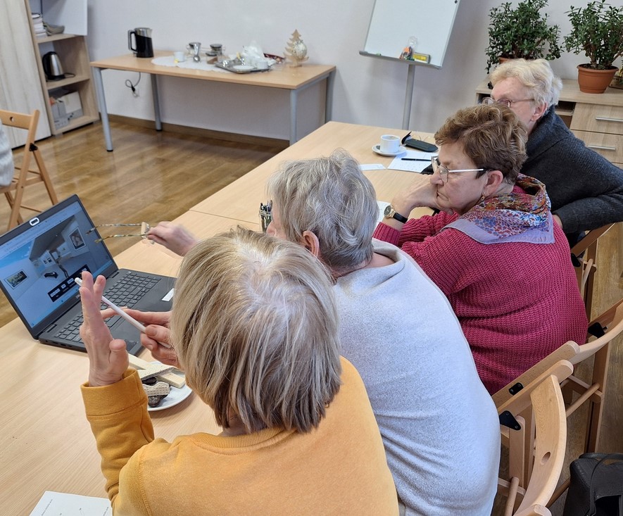 trzy kobiety siedzą przed komputerem w pomieszczeniu