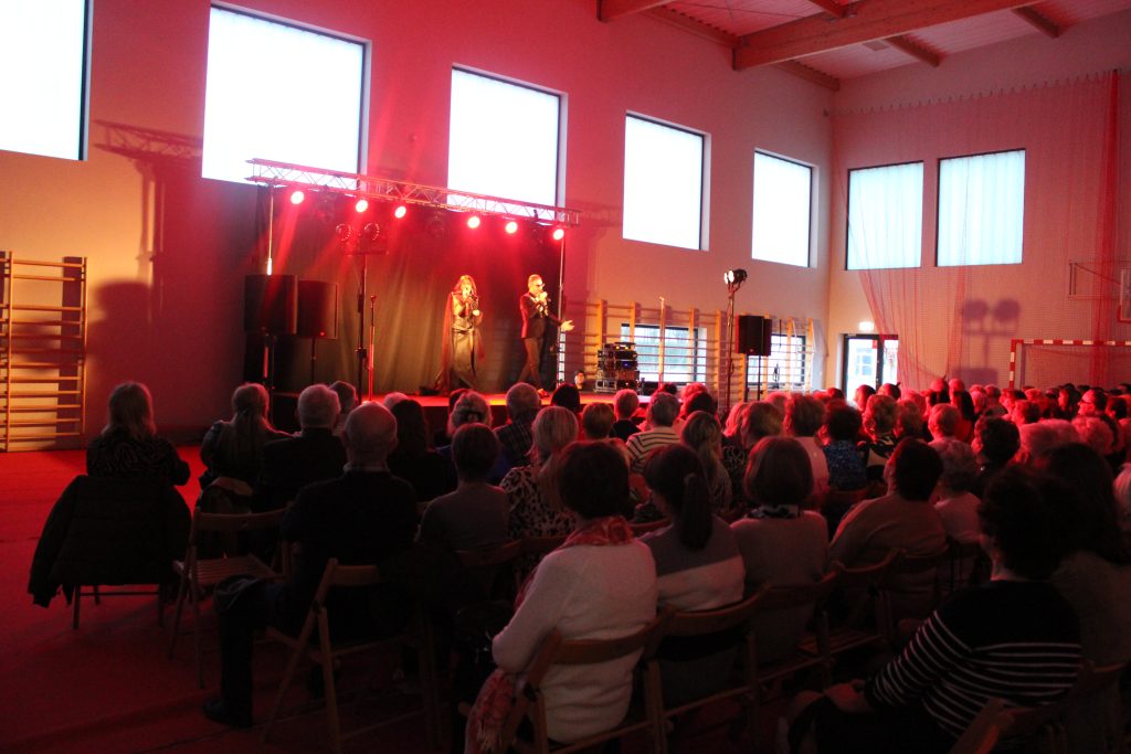 sala gimnastyczna, ludzie na krzesłach, scena, dwoje artystów