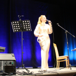 śpiewaczka z tamburynem stoi i śpiewa - Marta Grabowska , na pianinie gra Jacek Skowroński , na scenie , w budynku