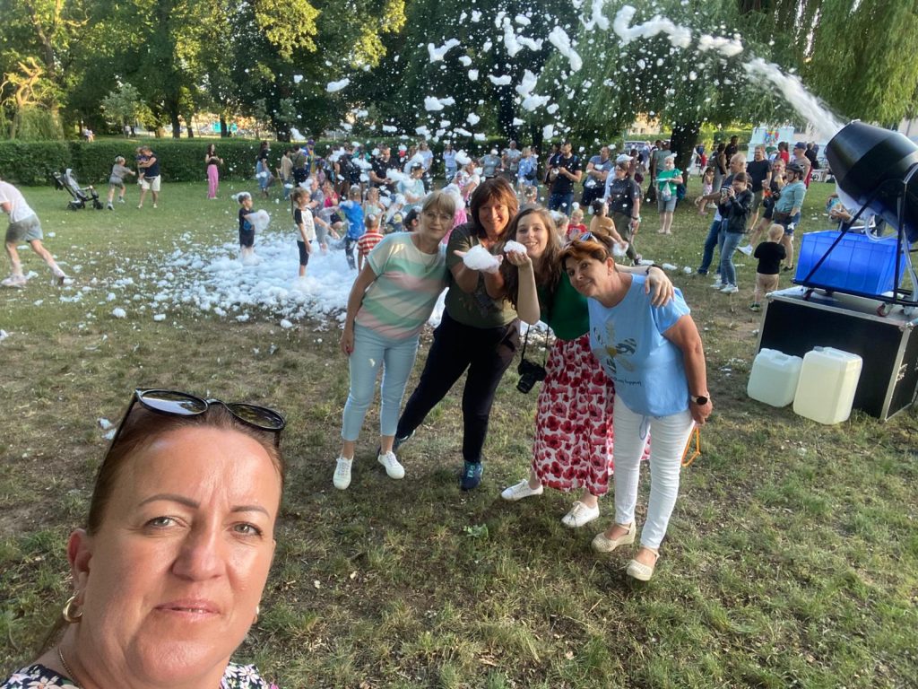 wyrzutnia piany, 5 osób pozuje do zdjęcia na tle bawiących się ludzi 