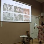 W sali prezentacja ze zdjęciami i prelegentka wskazuje na ekran