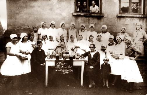 podpis kurs przetworów w Kaźmierzu 1931 r.
grupa kobiet pozuje do zdjęcia z przetworami na stoliku
zdjęcie stare czarno-białe