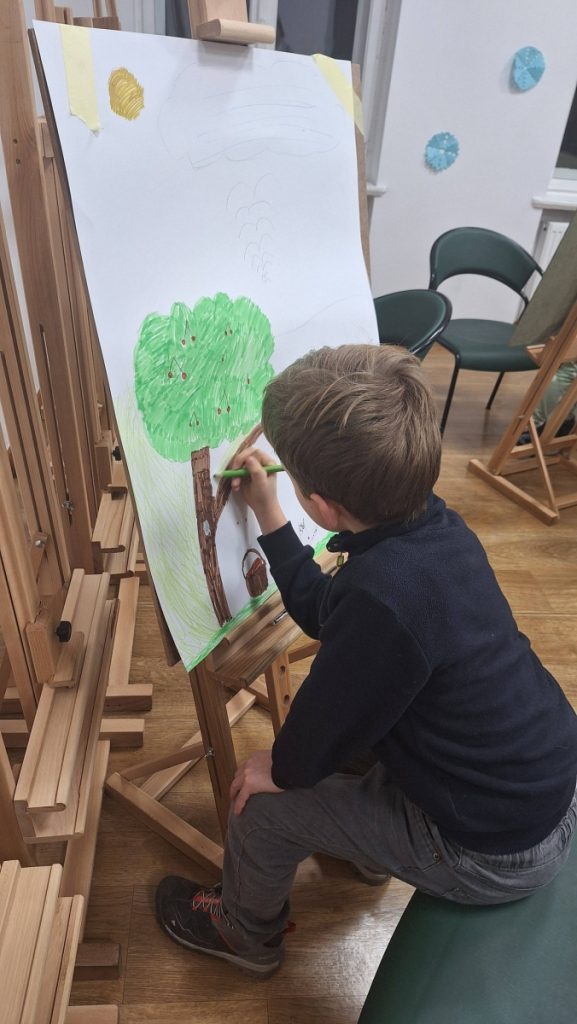 praca plastyczna dziecko  maluje przy sztaludze 