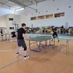 dwóch chłopców gra w tenisa stołowego na hali sportowej