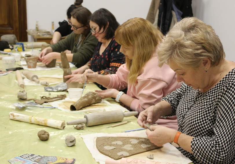grupa ludzi pracuje przy stołach, ceramika, w pomieszczeniu