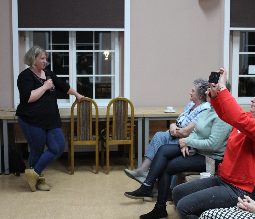 w budynku osoba z mikrofonem odpowiada na pytania słuchaczy