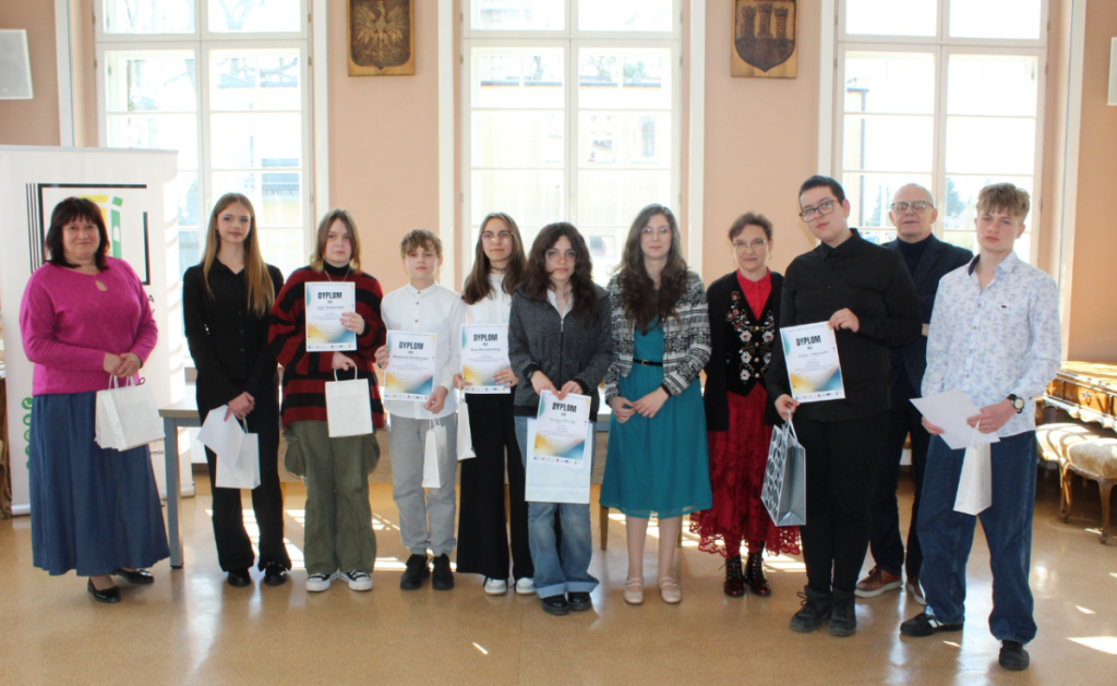 grupa ludzi dorośli i młodzież pamiątkowe zdjęcie z uczestnikami konkursu, dyplomy i nagrody