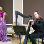 w sali, w centrum skrzypaczka i harfista