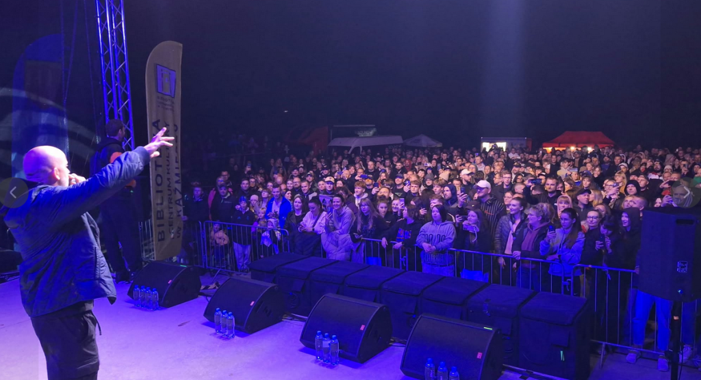 Mężczyzna na scenie , tłum pod sceną, ciemno 